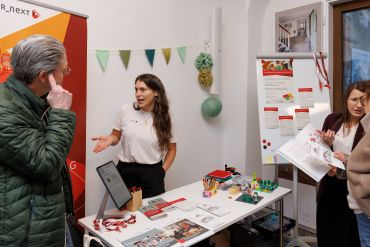 Das R_NEXT-Team steht verteilt vor oder hinter deren Ausstellungsstand und erklärt den Besuchenden des Schreiberhauses das Smart-City-Projekt.