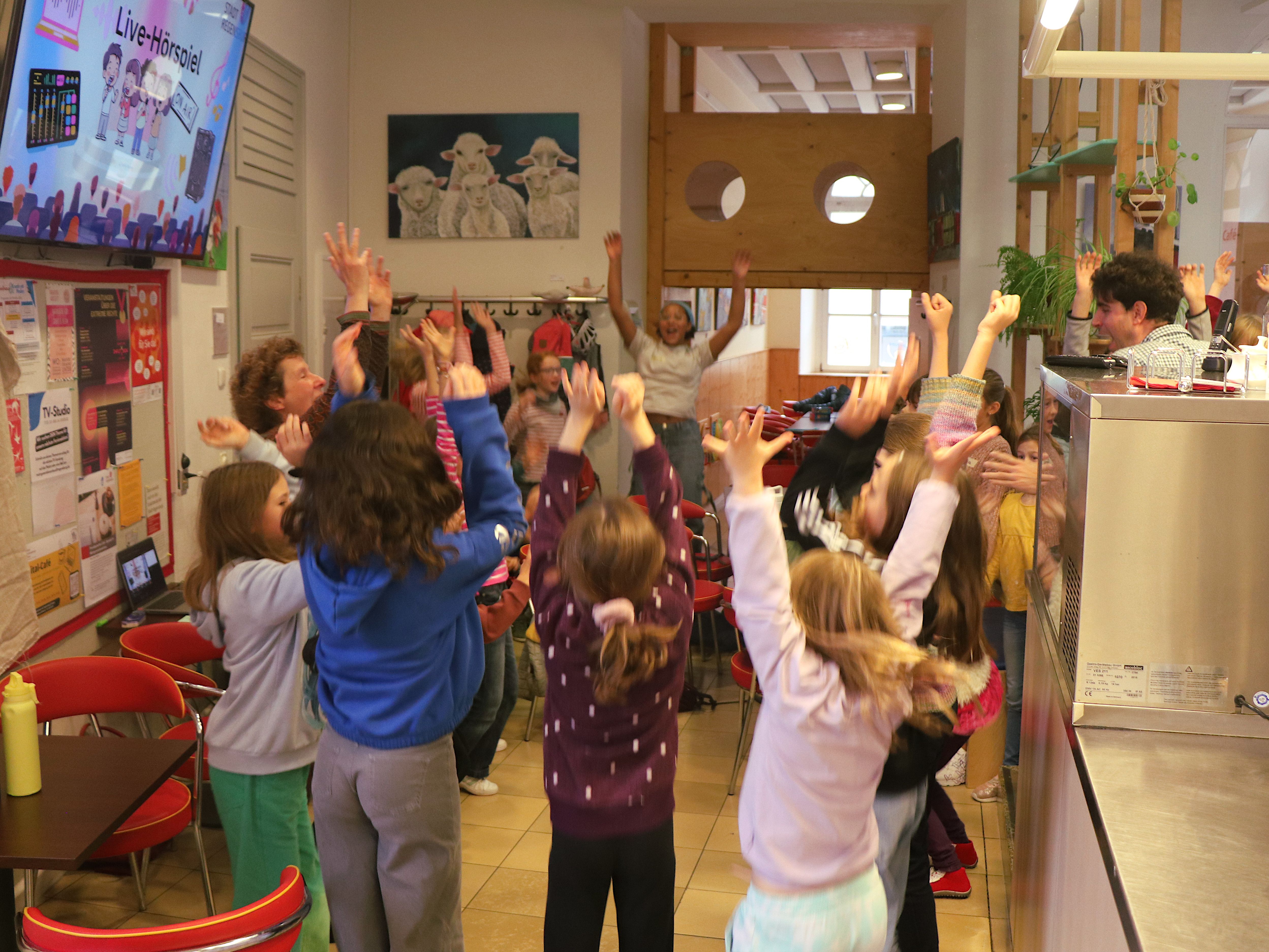 Kinder springen in einem Café in die Luft und strecken ihre Arme in die Höhe