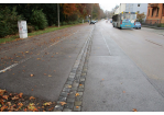 Prüfeninger Straße - Fotografie - im linken Bildbereich sieht man eine 3-zeilige Rinne aus Granitgroßsteinen, die große Schäden aufweist 