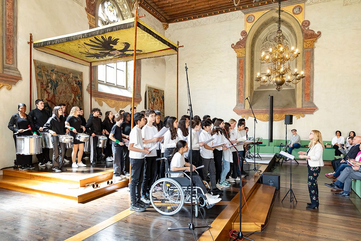 Fotografie - Das Ensemble des Collège La Charme und die Samba Bateria Feijoada der Clermont-Ferrand-Mittelschule zusammen mit der französischen Dirigentin Marie-Claire Kondo.