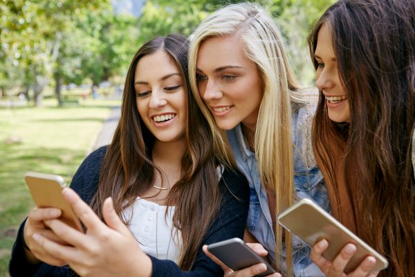 Fotografie: Drei junge Frauen schauen in ein Smartphone.