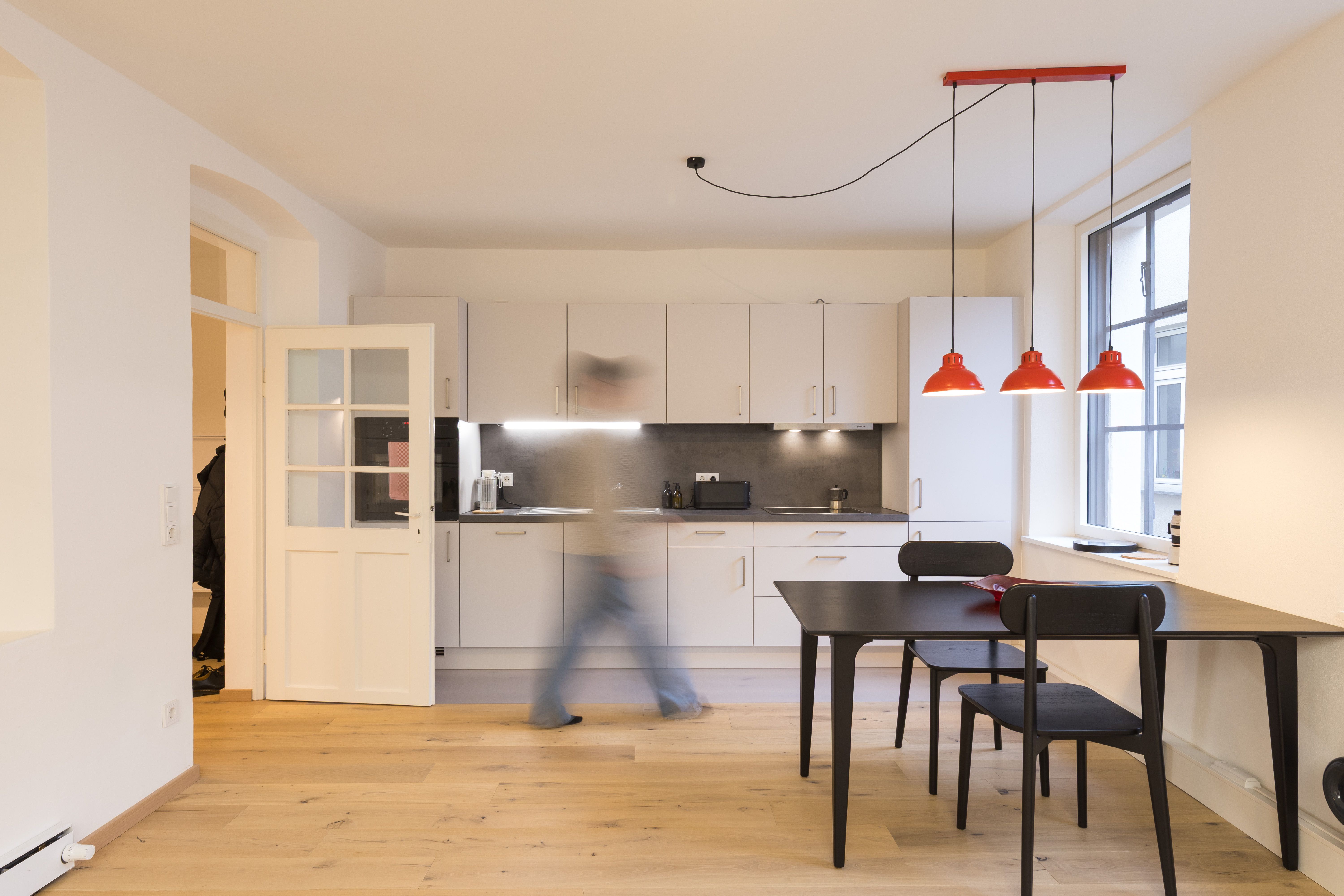 Fotografie - Atelierwohnung 2 - Zu sehen ist eine verschwommende männliche Silhouette, die durch die Küche läuft.