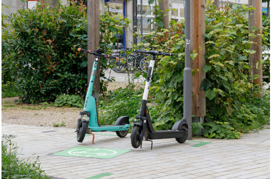 Fotografie: Zwei E-Scooter stehen auf einem Abstellplatz.