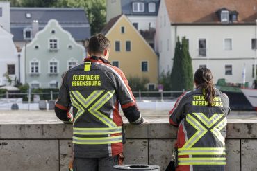 Fotografie: Ein Feuerwehrmann und eine Feuerwehrfrau blicken auf die Donau.