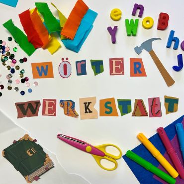 Bastelmaterial und bunte Farben, in der Mitte der Schriftzug "Wörterwerkstatt"